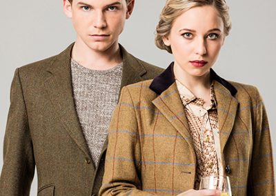 Male and female models dressed in tweed jackets, the woman is holding a cocktail glass