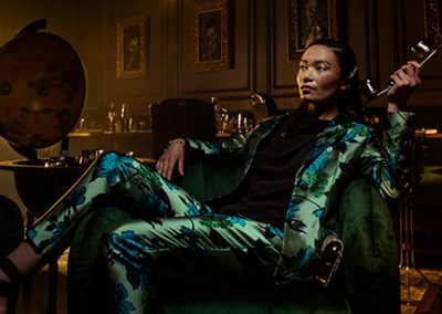 Model lounges on sofa in blue silk suit holding a telephone